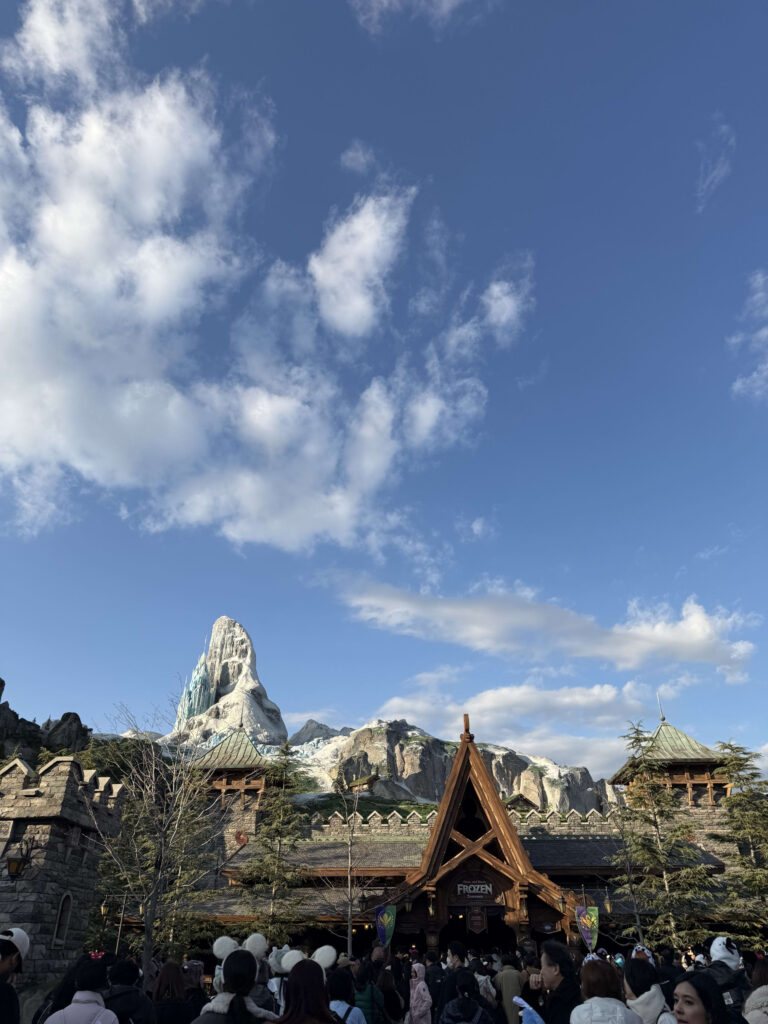 The entrance to Anna and Elsa's Frozen Journey attraction with the snowy North Mountain towering in the background under a blue sky