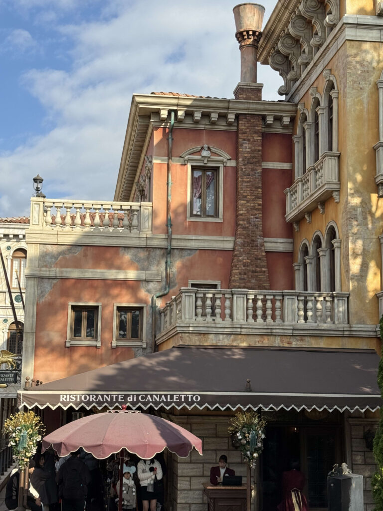 Exterior view of Ristorante di Canaletto featuring orange walls, a brick chimney, and Venetian architecture under a blue sky