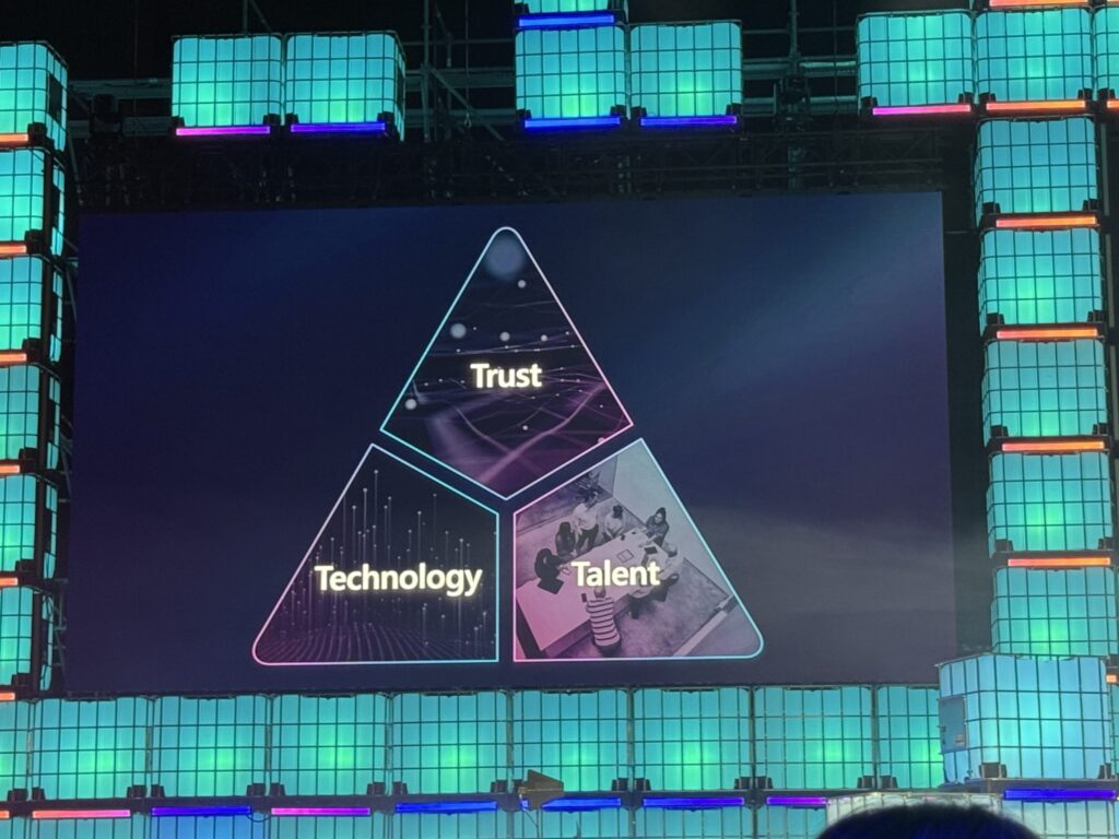 A presentation slide on a large screen showing a triangle divided into three parts labeled Trust, Technology, and Talent during a Microsoft keynote.