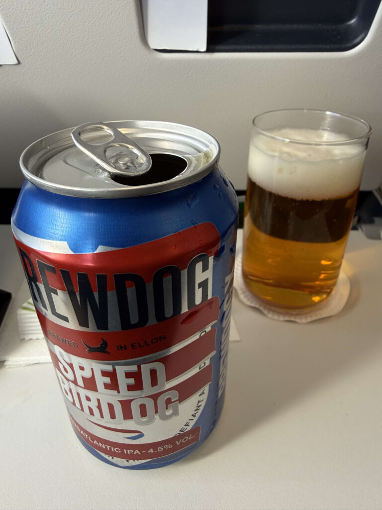 機内のトレイテーブルに置かれたブリュードッグの缶ビール「SPEEDBIRD OG」と、ビールが注がれたグラス
