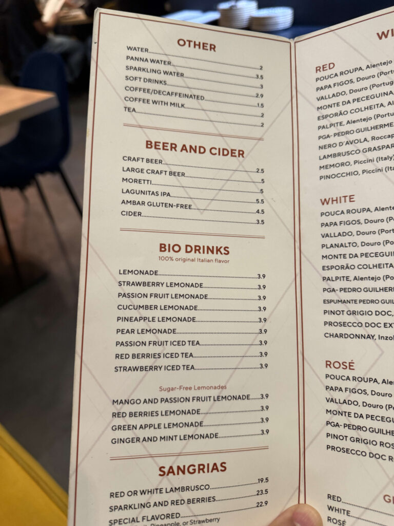 Close-up photo of a restaurant drink menu showing sections for Other, Beer and Cider, Bio Drinks, and Sangrias with prices.