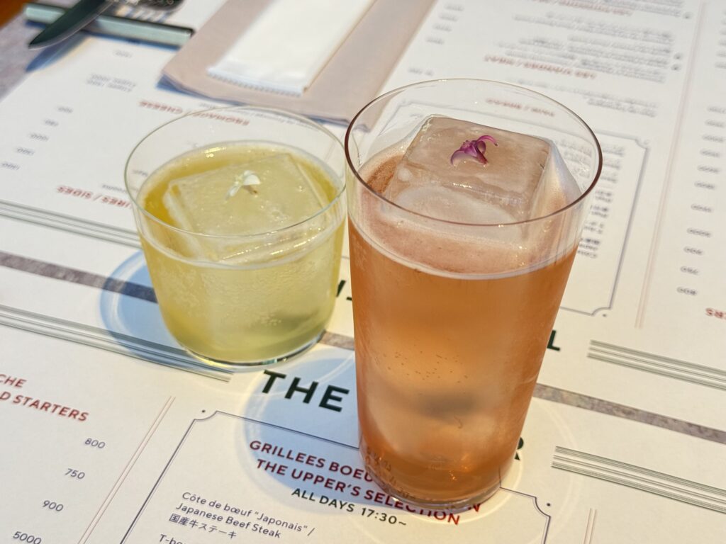 Two types of mocktails, Muscat Soda and Peach Claw, placed on a restaurant menu