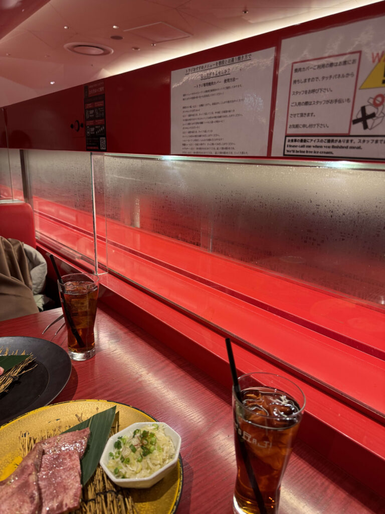 焼肉トラジイクスピアリ店の赤い特急レーンとテーブルに並ぶ肉やドリンク