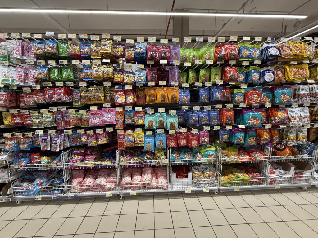 ヨーロッパのスーパーマーケットで、棚一面に陳列された色とりどりのグミやキャンディ