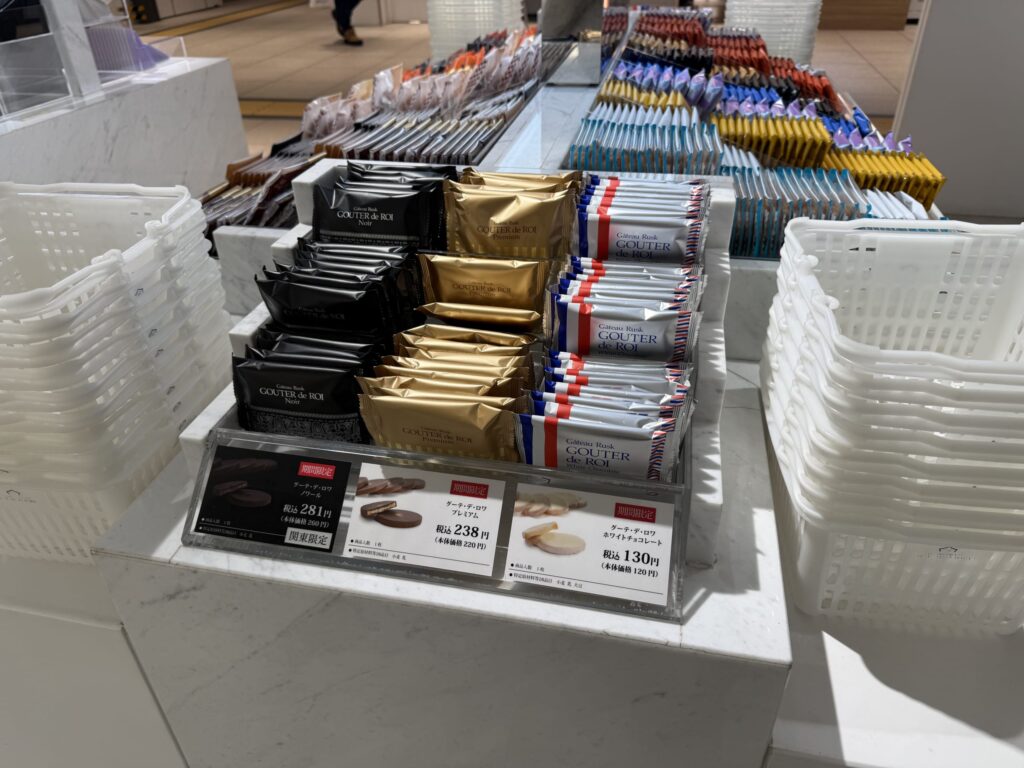 Display shelf featuring Gateau Festa Harada rusks, including Noir, Premium, and White Chocolate flavors, arranged between stacks of white baskets