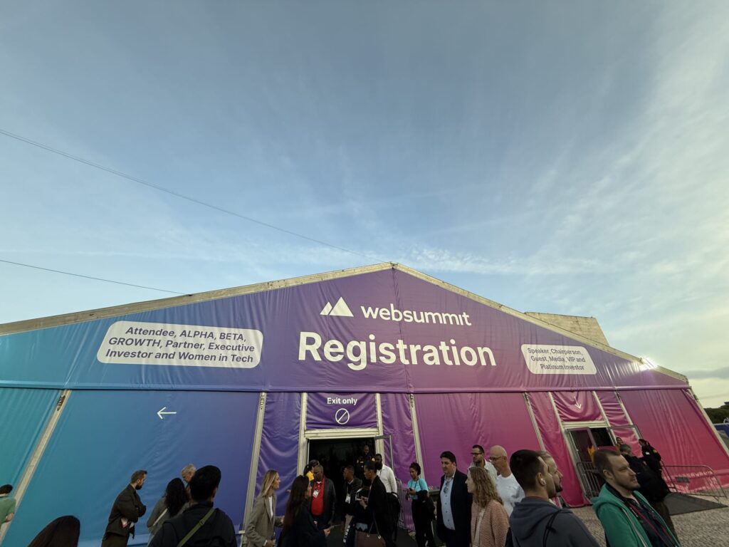 The massive registration tent for Web Summit featuring a blue and purple gradient banner, with people gathered near the 