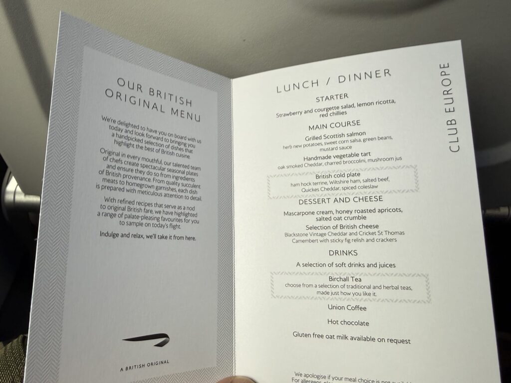 Open British Airways Club Europe in-flight menu card showing lunch and dinner options including grilled Scottish salmon, vegetable tart, and a British cold plate.