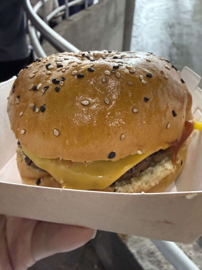 紙箱に入った、白と黒のゴマ付きバンズのチーズバーガー