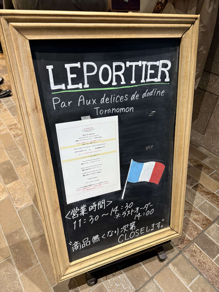 Wooden menu signboard for the French restaurant LE PORTIER in Toranomon, displaying lunch options and business hours.