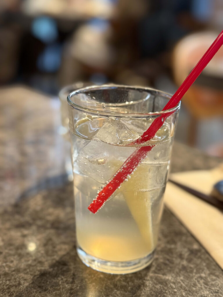 Glass of lemongrass ginger soda with ice and a red straw