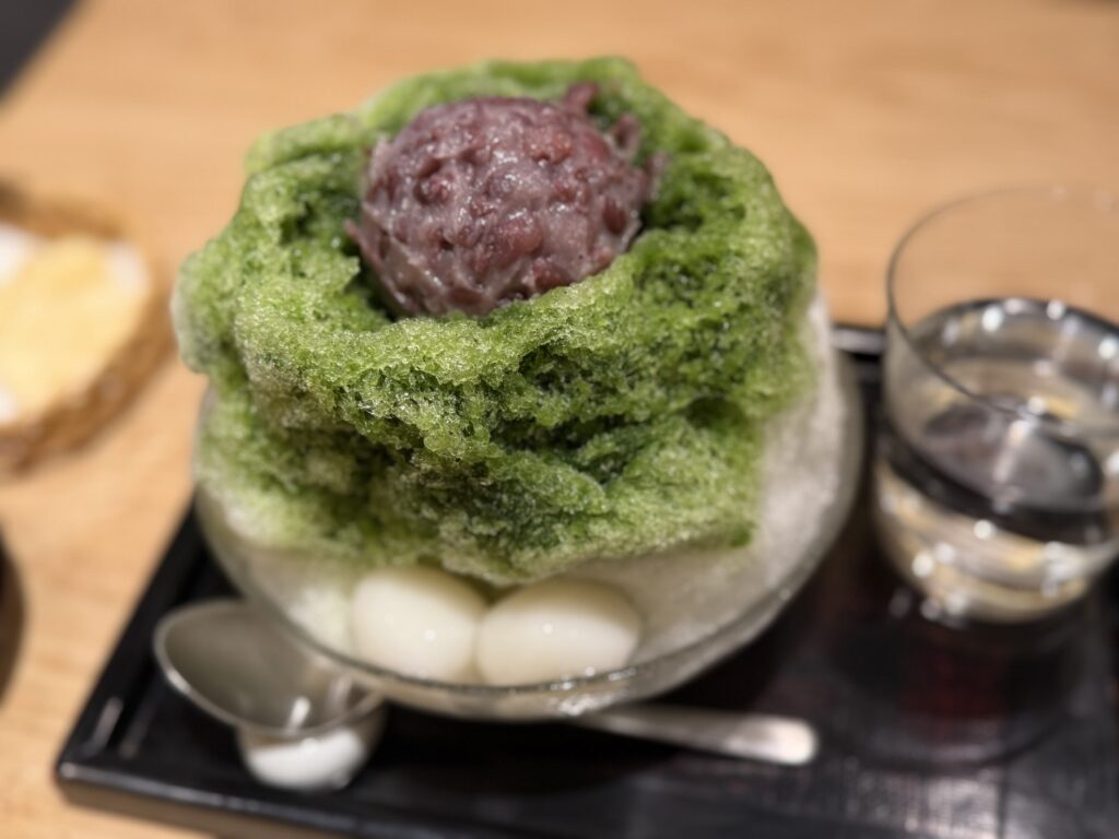 鮮やかな緑色の抹茶シロップがかかったかき氷に、たっぷりの粒あんと白玉が添えられた宇治金時