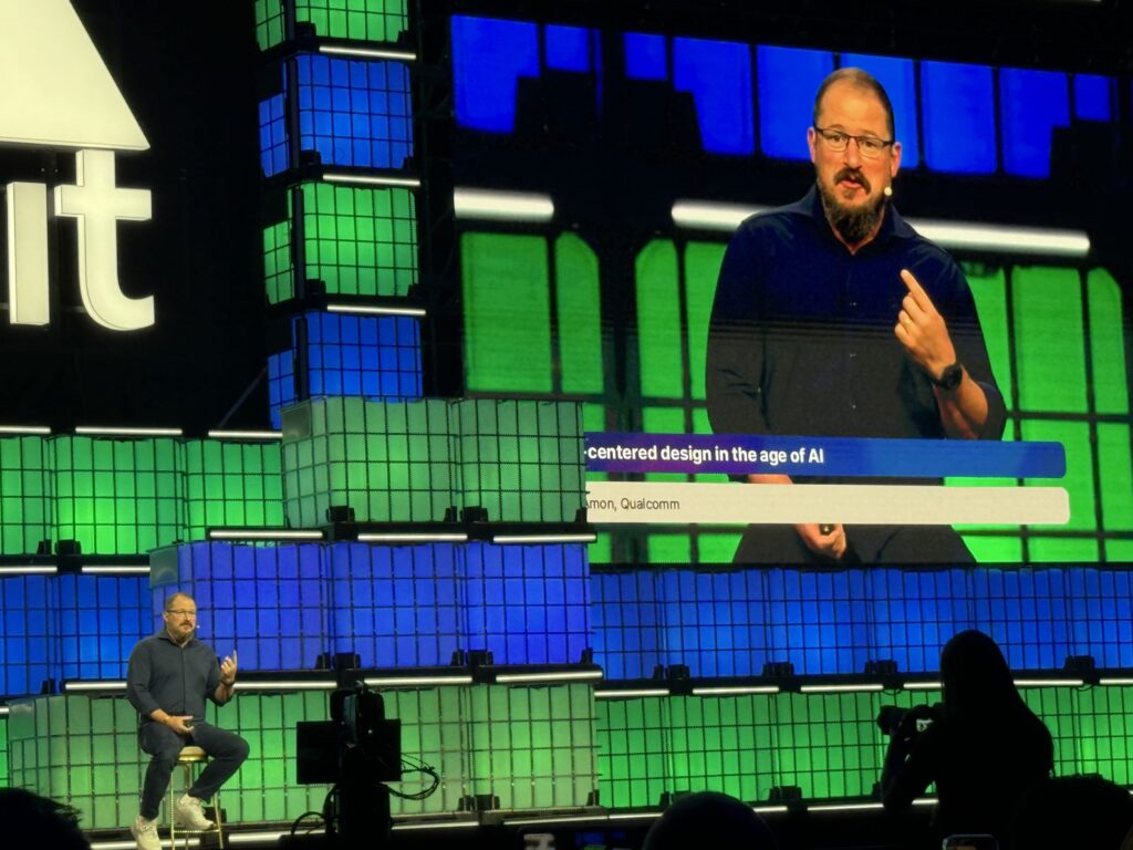 ステージ上のスツールに座り、背後の巨大スクリーンに自身の姿が映し出される中、講演を行うクアルコムのCEO、クリスティアーノ・アモン氏。