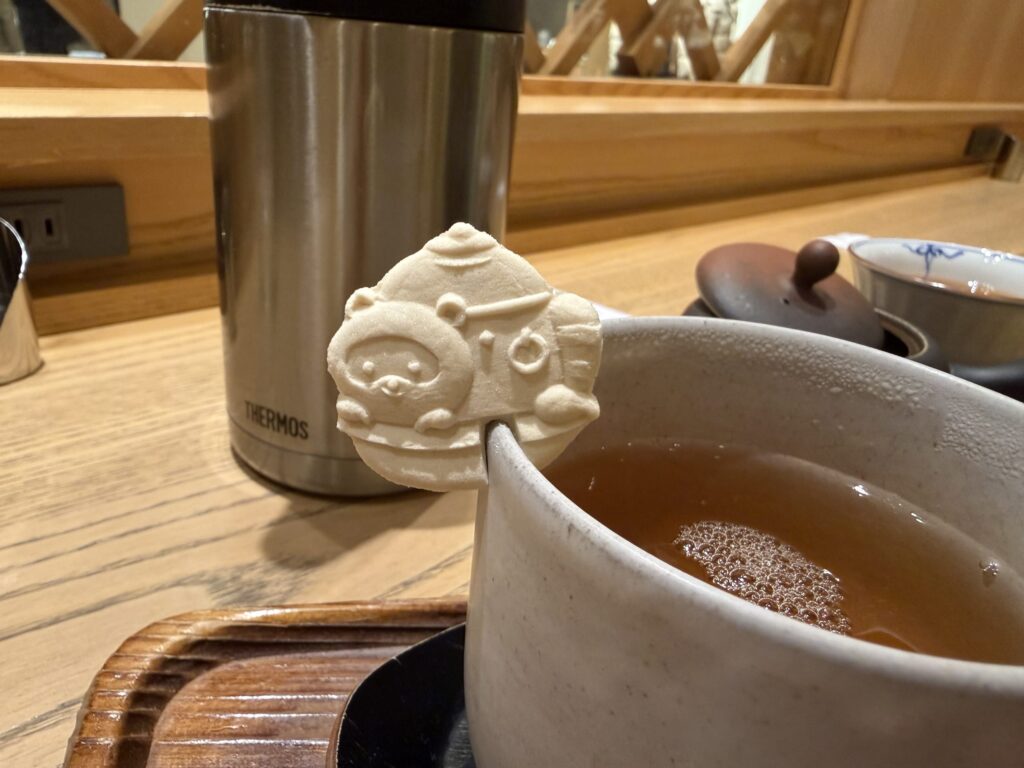 お茶の入った湯呑みの縁にちょこんと乗った熊の形をした最中