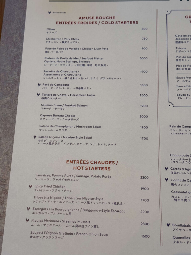 Restaurant a la carte menu listing cold and hot starters with prices and descriptions in French, English and Japanese