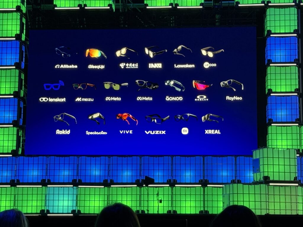 Large presentation screen displaying a lineup of smart glasses brands and models supported by Qualcomm