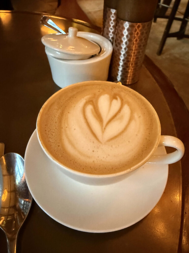 Almond milk cappuccino with tulip latte art in a white cup on a wooden table