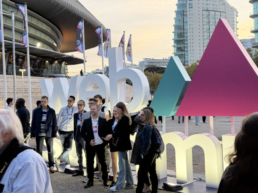 Group of attendees posing for a photo in front of the large Web Summit logo sign