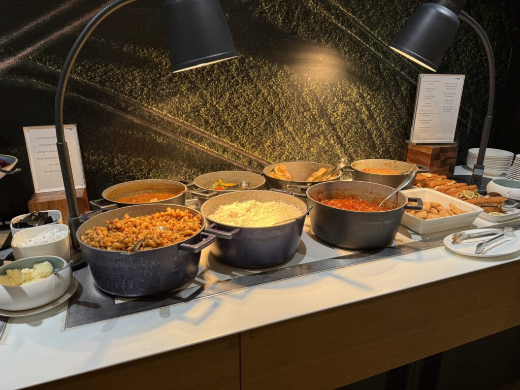 ブッフェのホットミールコーナー。パスタ、ライス、カレーなどの温かい料理が大きな鍋に入って並んでいる様子