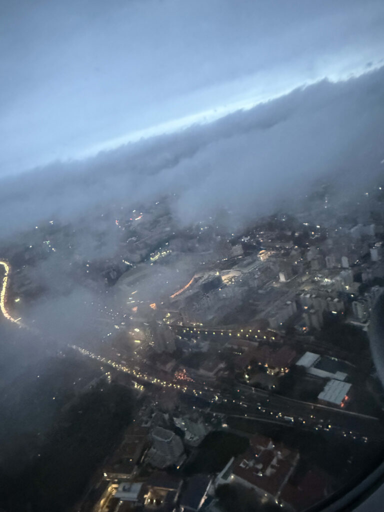 飛行機の窓から見下ろす、雲の隙間に輝くリスボンの街明かり