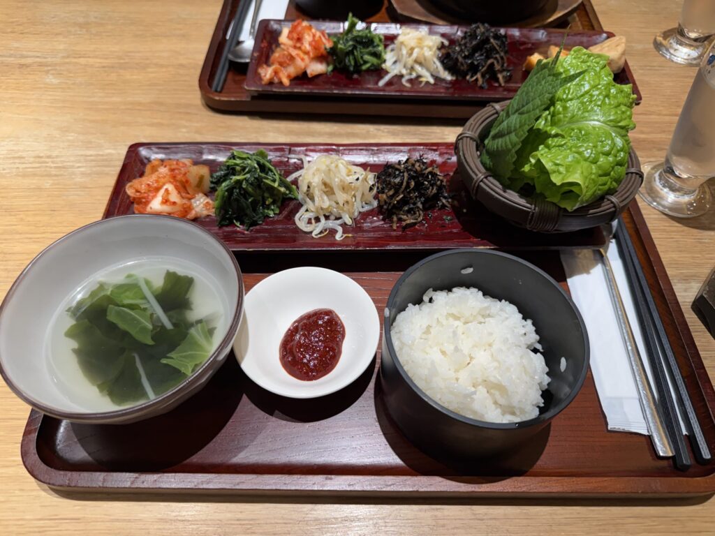 Bulgogi set meal arrangement featuring namul, kimchi, rice, seaweed soup, and fresh lettuce for wrapping