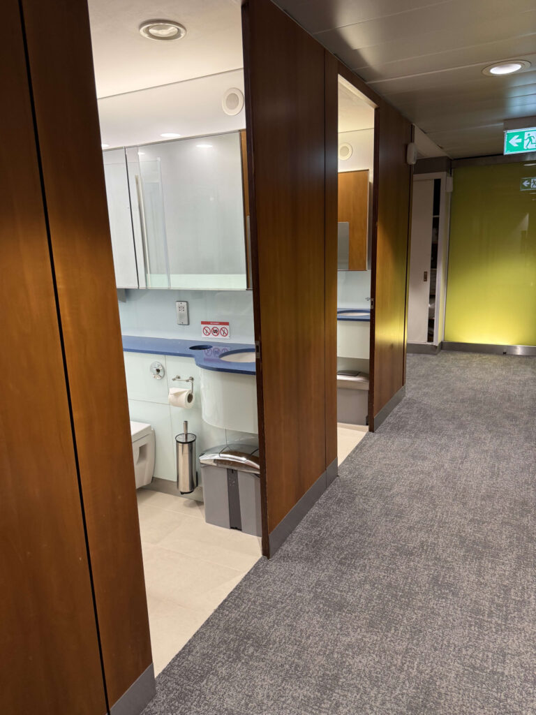 Entrance to a modern restroom and shower facility featuring wooden partitions and a sink area