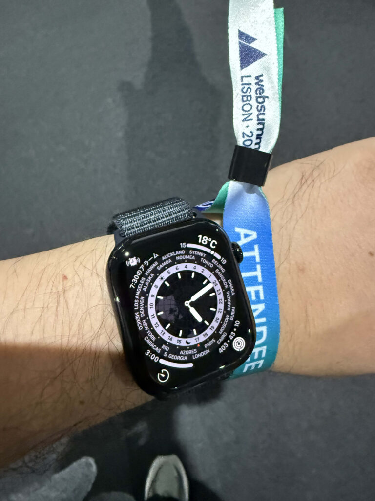Web Summit Lisbonの参加者用リストバンドとワールドタイムを表示したApple Watchを装着した手首