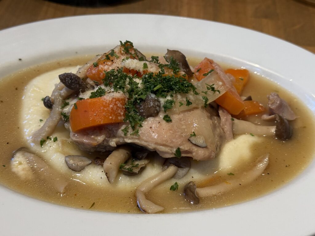 マッシュポテトの上に盛り付けられた鶏もも肉ときのこの白ワイン煮込み