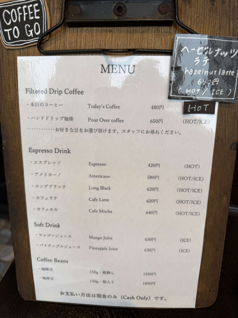 木目のクリップボードに挟まれたカフェのドリンクとコーヒー豆のメニュー表