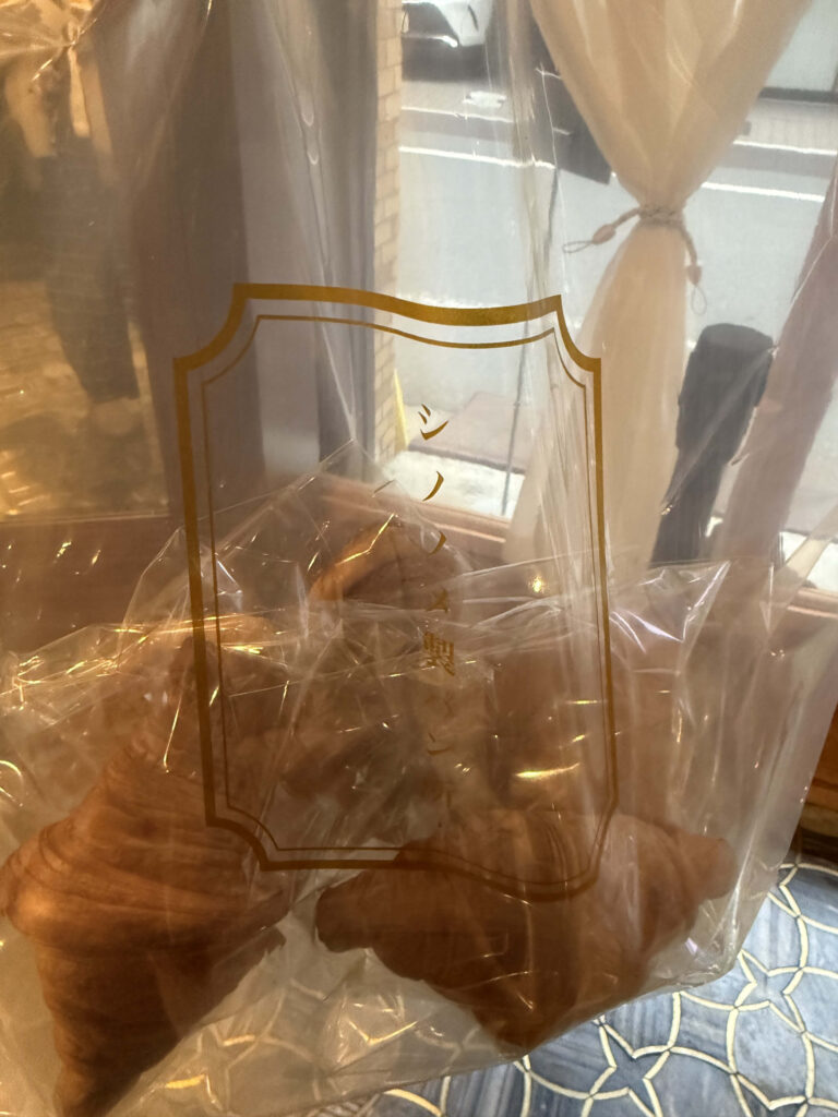 Freshly purchased croissants with golden layers inside a clear bag with a logo
