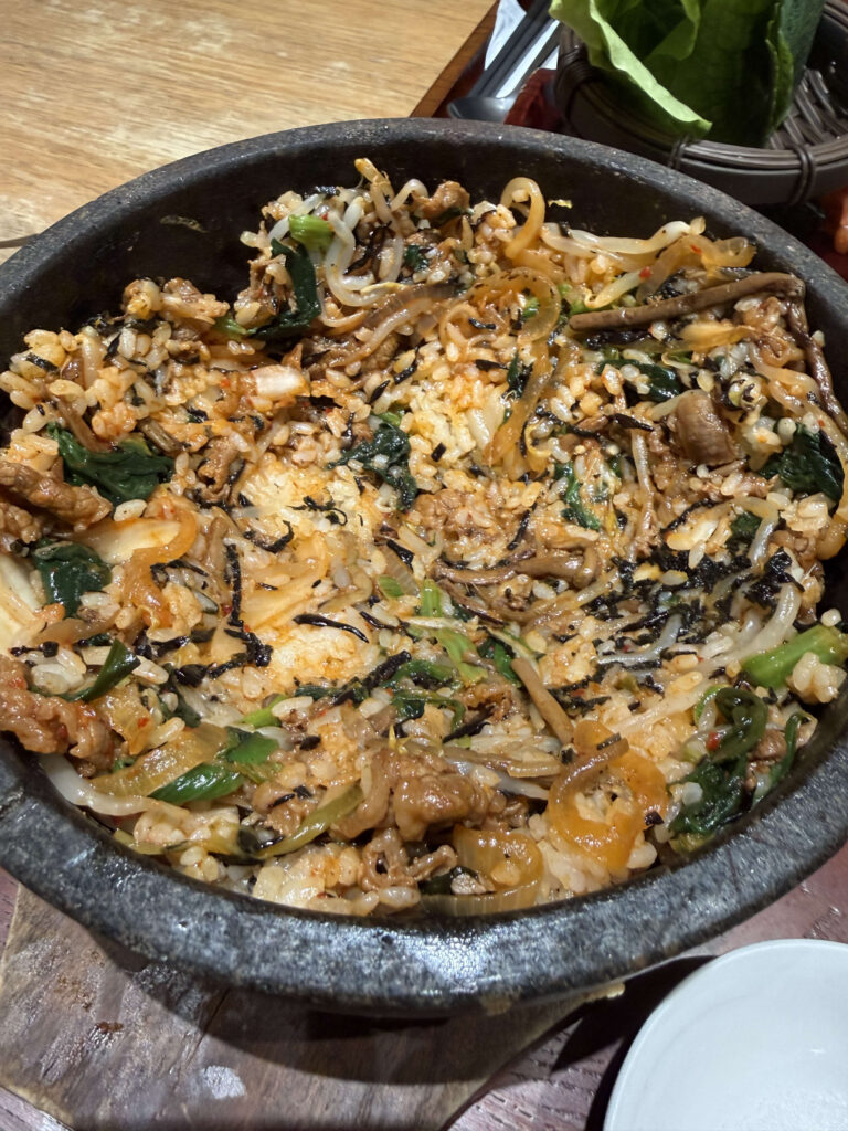 熱々の石鍋の中で具材とご飯がよく混ぜ合わされた石焼ビビンパのクローズアップ