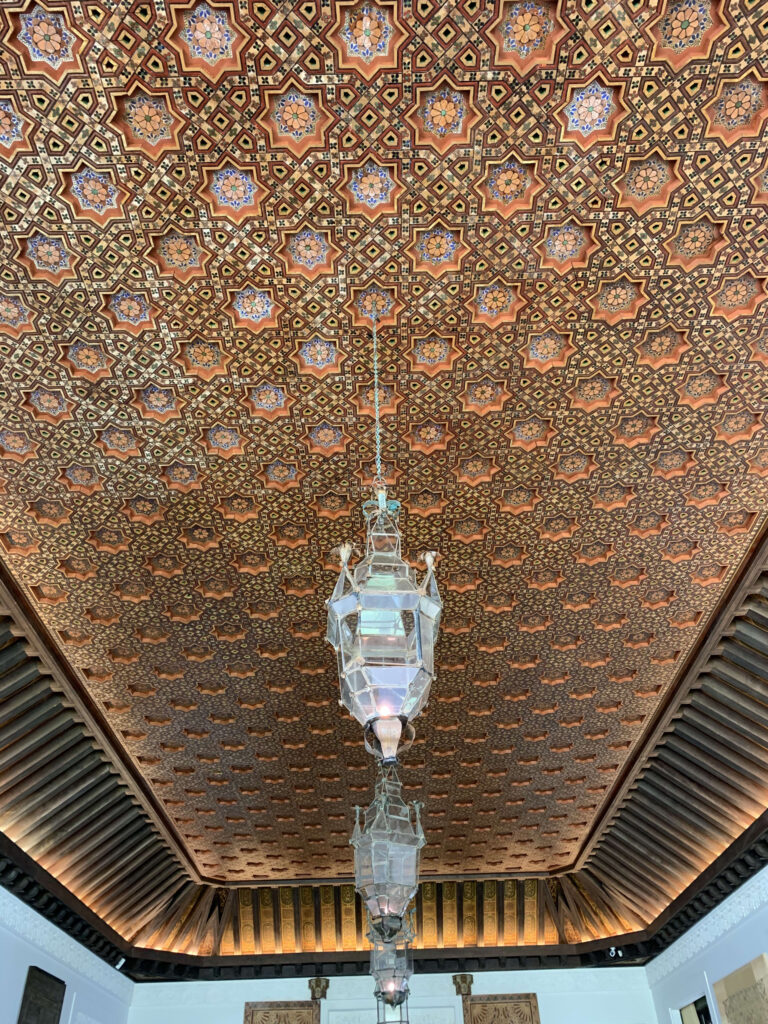 Intricate wooden ceiling featuring colorful geometric star patterns and a hanging lantern