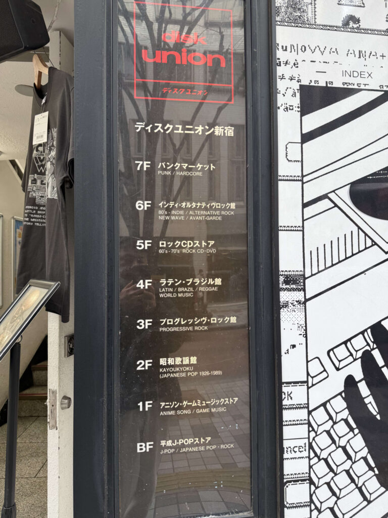 Floor guide sign at the entrance of Disk Union Shinjuku, listing music genres for floors B1F through 7F.