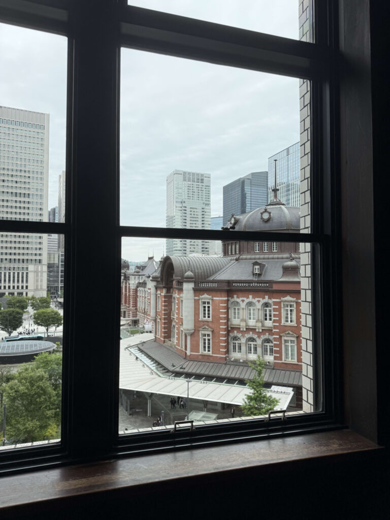 View of the red brick Tokyo Station building and dome roof seen through a black window frame