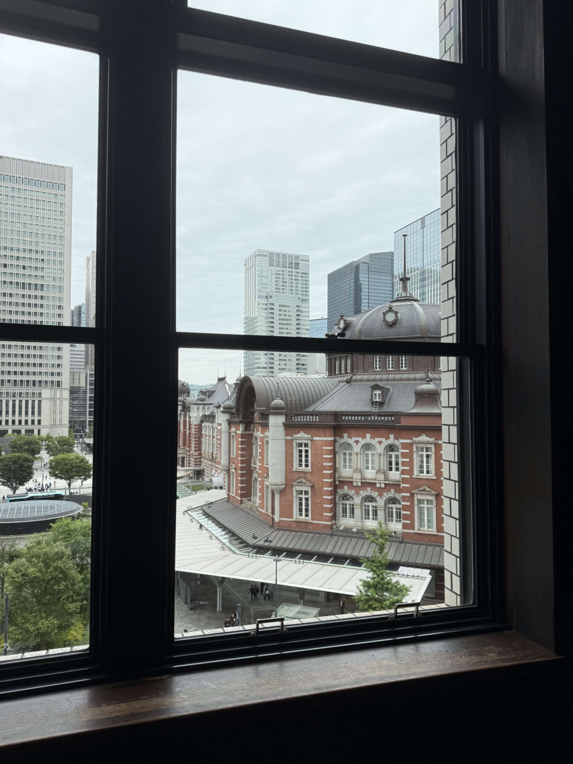 View of the red brick Tokyo Station building and dome roof seen through a black window frame