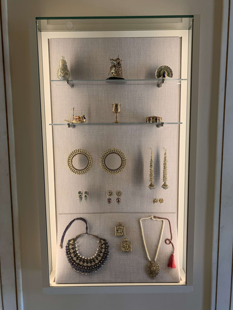 ショーケースに展示されたゴールドのネックレス、ピアス、腕輪などの宝飾品と工芸品