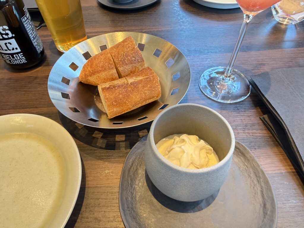 銀色のボウルに入ったバゲットと、豆乳と湯葉のムース 和からしエスプーマ