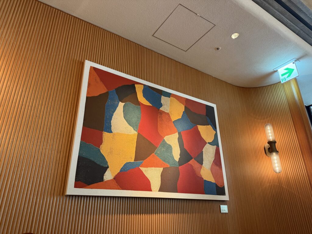 A colorful abstract painting hanging on a textured wooden wall with vertical slats