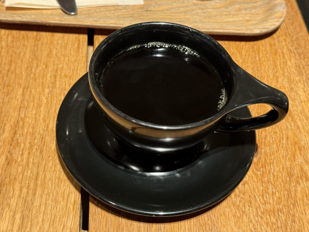 木目のテーブルに置かれた、黒いカップに入ったエチオピアモカのデカフェコーヒー