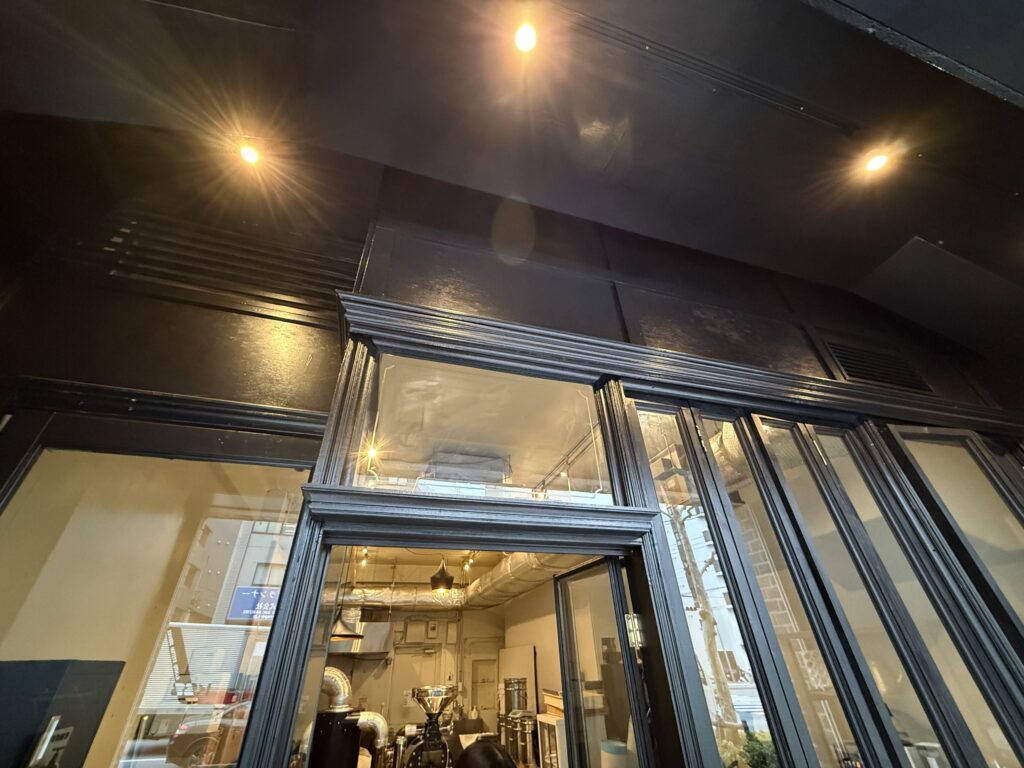 Upper facade of a shop painted in black with warm downlights