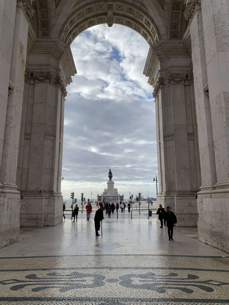 View of Praça do Comércio and the statue of King José I framed by the massive pillars of the Arco da Rua Augusta in Lisbon.