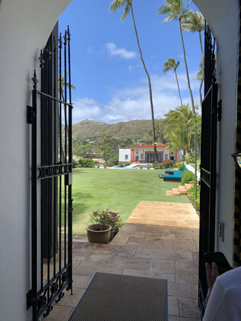 View of Diamond Head and a lush green garden framed by open black iron gates