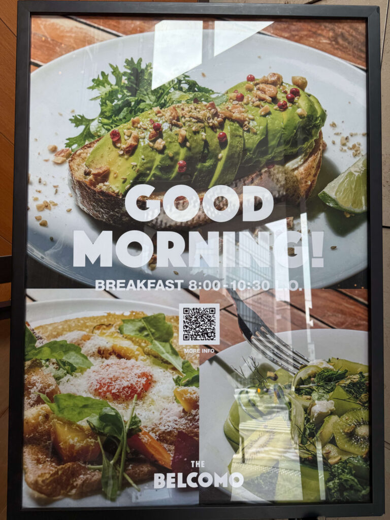 アボカドトースト、ガレット、サラダの写真と「GOOD MORNING!」の文字が書かれたTHE BELCOMOの朝食メニュー看板