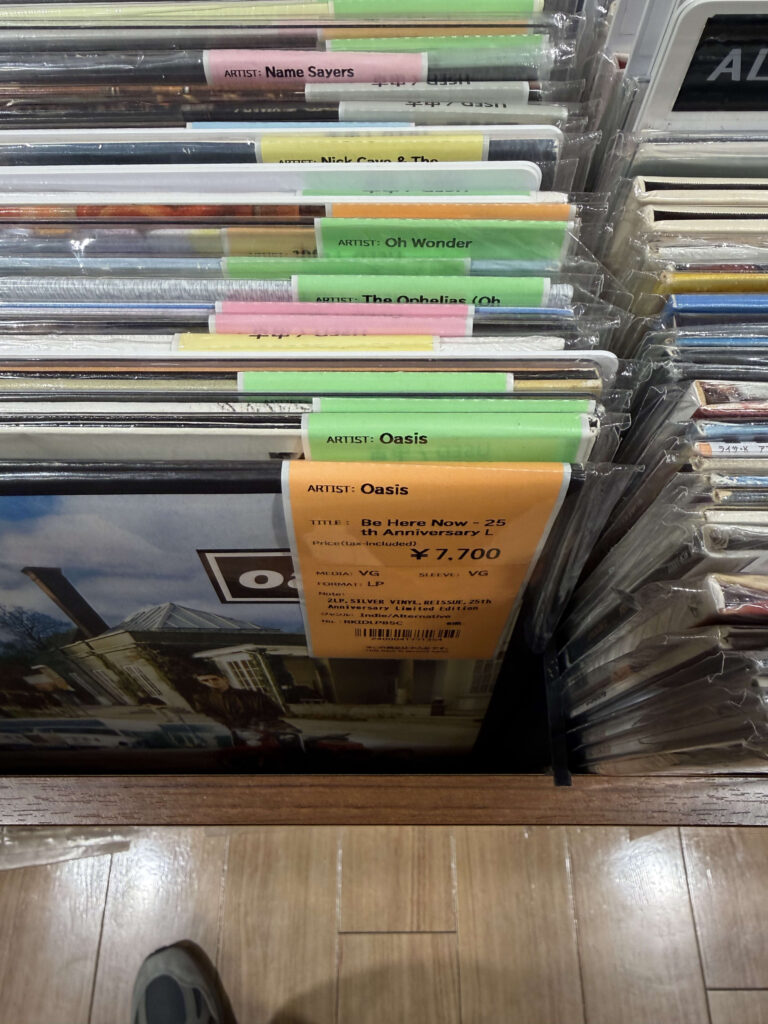 レコード店の棚に並ぶオアシスのアルバム『Be Here Now』25周年記念シルバー盤と価格タグ