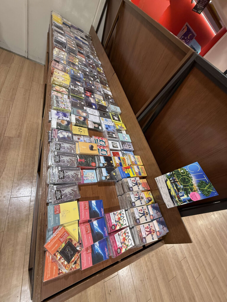 店内の木製棚に平置きされた山下達郎の『SPACY』や『RIDE ON TIME』など、多数のシティポップ・カセットテープ