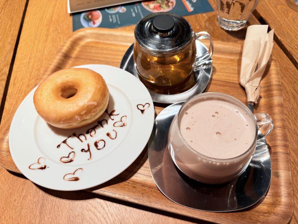 木製トレー上のシュガードーナツ、ミルクショコラ、ルイボスティー。「Thank you」のチョコ文字入りプレート