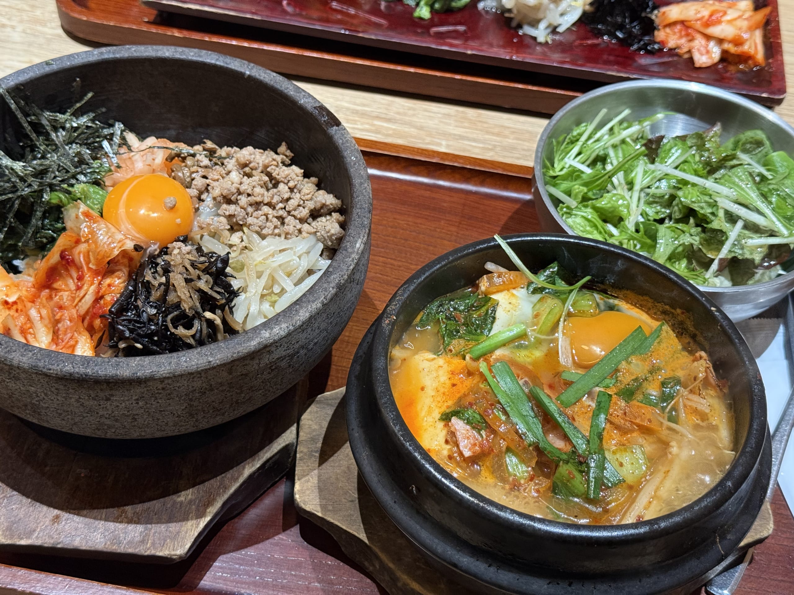 卵黄やキムチ、ひき肉が乗った全州石焼ビビンパと、ベーコンと野菜が入った特選チゲ、グリーンサラダのセット