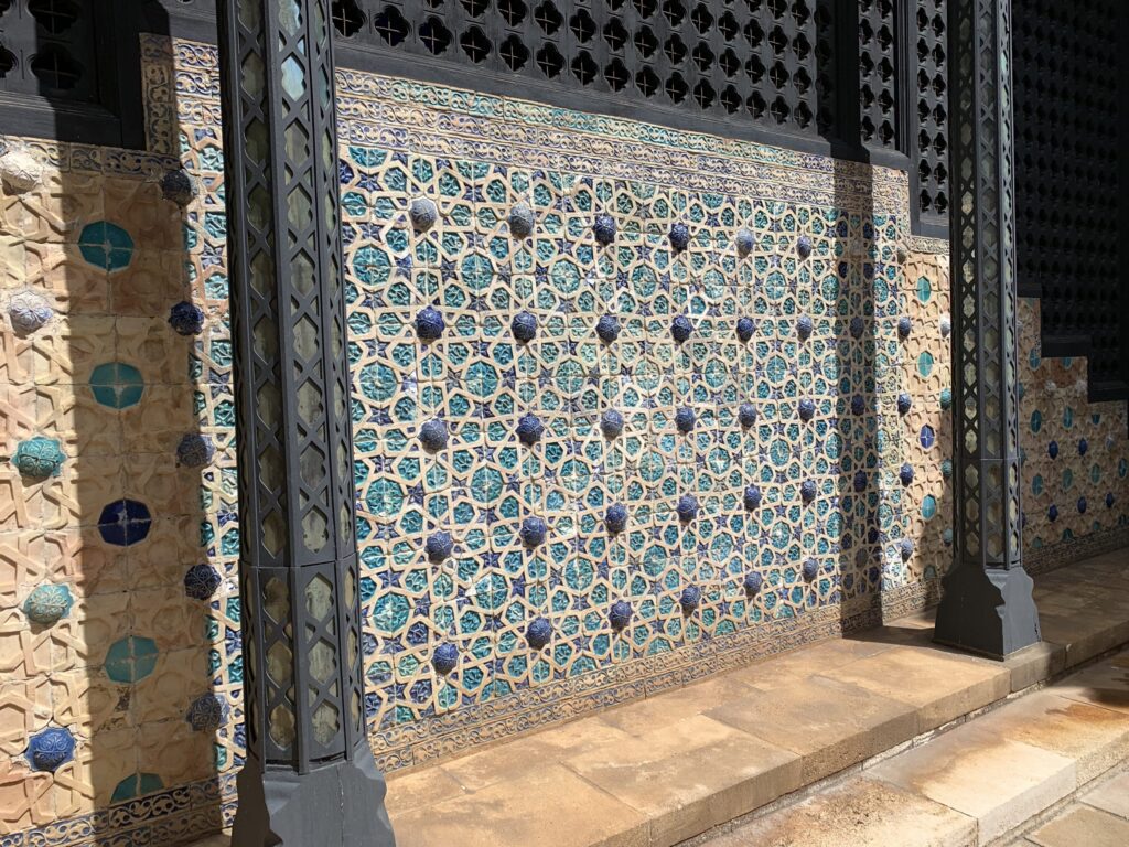 Wall of the Central Courtyard featuring intricate blue star-shaped geometric tiles and dark lattice pillars