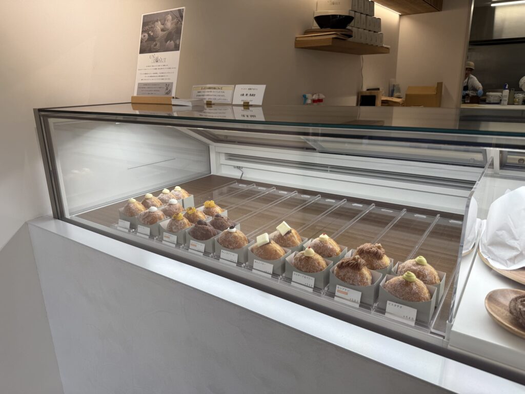 A variety of round donuts topped with cream and butter displayed neatly in a clean glass showcase