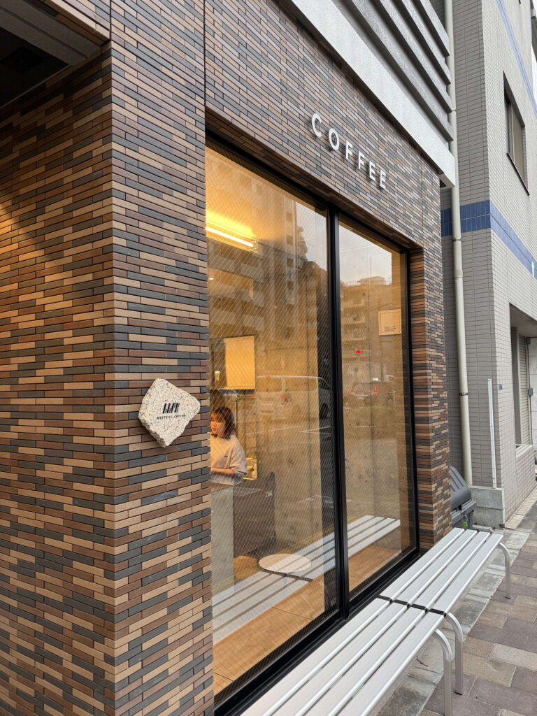 蔵前にあるWESTSIDE COFFEEのスタイリッシュなレンガ造りの外観と大きなガラス窓、店先のベンチ