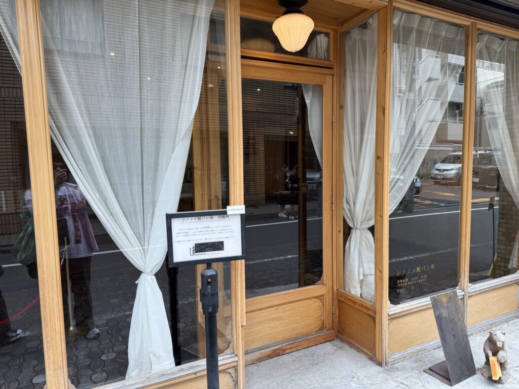 シノノメ製パン所の木製の外観と白いカーテン、入店制限の案内看板